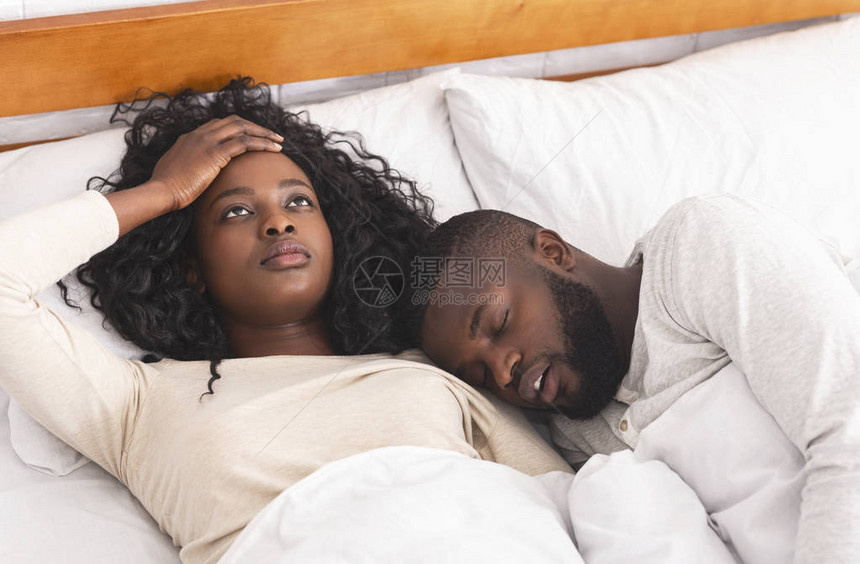 沮丧的年轻女子被丈夫在床上大声打呼噜而烦恼图片