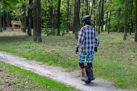 身穿防护服的嬉皮士在农村土路旁骑着电子单轮车带有复制空间的图片