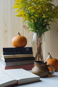 秋天的生活还有堆叠的书橙南瓜勺子粘土饮料杯固体花束垂直储量照背景图片