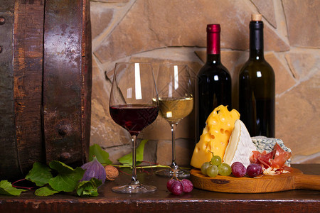 红白葡萄酒与葡萄在酒窖的旧木桶旁边图片