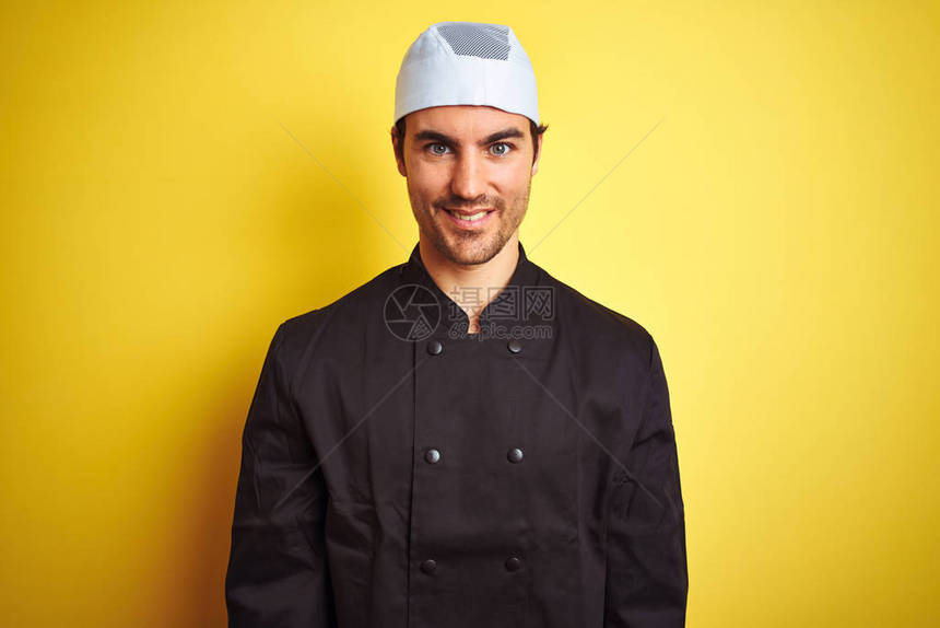 英俊的厨师长穿着制服和帽子在孤立的黄色背景上做饭图片