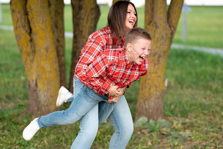妈笑得很开心抱着一个笑儿子在她怀里把她的背压到自己身上图片