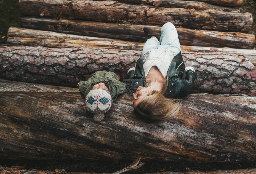 秋林中躺在一堆原木上的母亲和小女孩的秋天肖图片