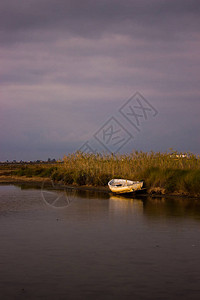 岸边的废弃小船与云彩天空的日落图片