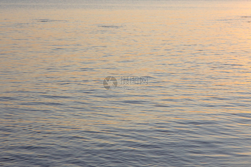 蓝色和橙色的清水纹理海洋和海的背景被太阳图片