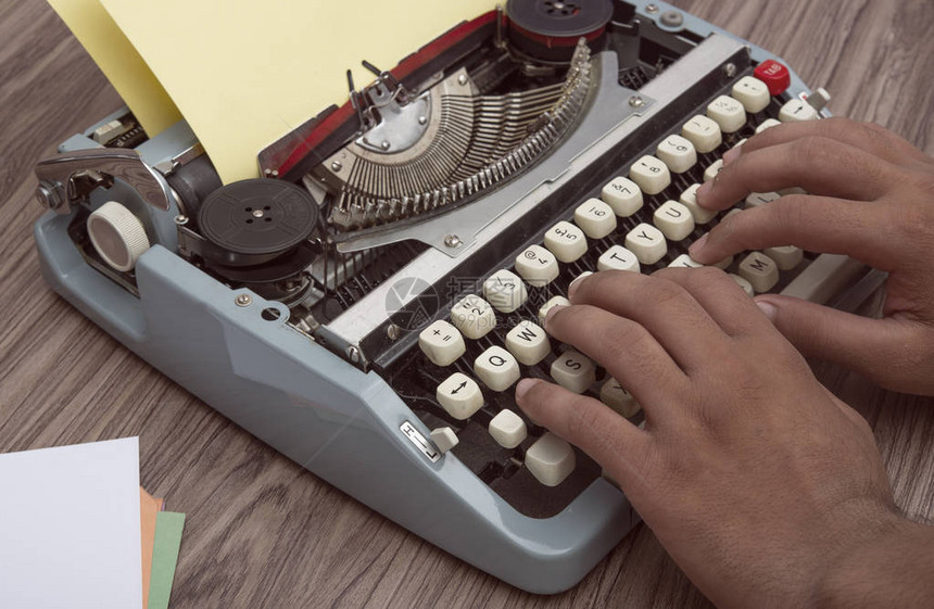 手在木制背景的旧打字机上书写图片