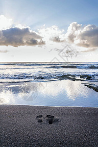 人类赤脚印在沙滩上等待海浪图片