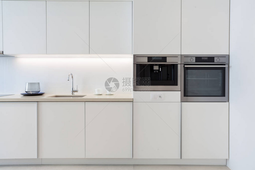 白色现代公寓与现代内饰在厨房新型家用电器台面上带铬水龙头的水槽电烤箱和光面图片