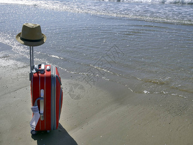 海边滩上挂着帽子的旅行李箱周末的概图片