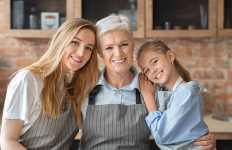 母亲女儿和祖母在烹饪时拥抱厨房图片
