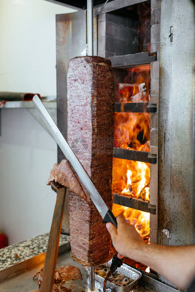传统土耳其烤肉串厨师用刀沙威玛或陀螺仪切割土耳其希腊或中东阿拉伯风格的烤肉串食图片