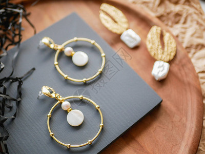 金耳环女饰品复古装饰背景漂亮的金色胸针手镯项链和耳环放在木托盘上图片