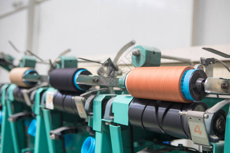 纺织厂整经机上的一组梭芯线锥在一家纺织厂制作纱球纺织工业纺织厂纺背景