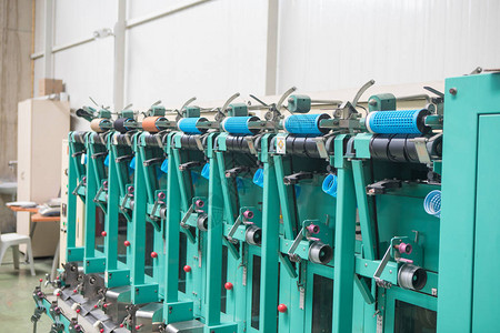纺织厂整经机上的一组梭芯线锥在一家纺织厂制作纱球纺织工业纺织厂纺背景