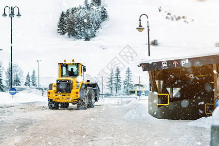 带钢金属链的大型装载机在冬季从高山区城市街道上清除大雪堆图片