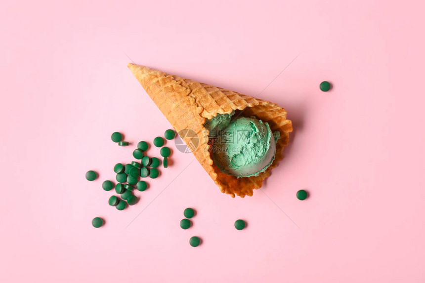 彩色背景上带有美味螺旋藻冰淇淋的华夫蛋筒图片
