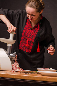 在厨房里用研磨机准备碎肉的女人图片