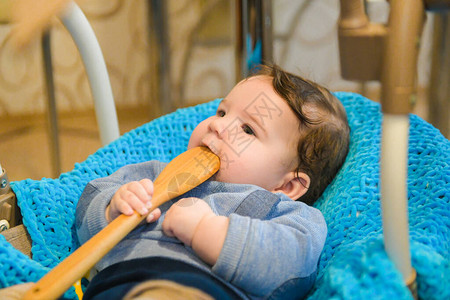 这孩子咬着木勺子新生儿在床上嚼着木图片