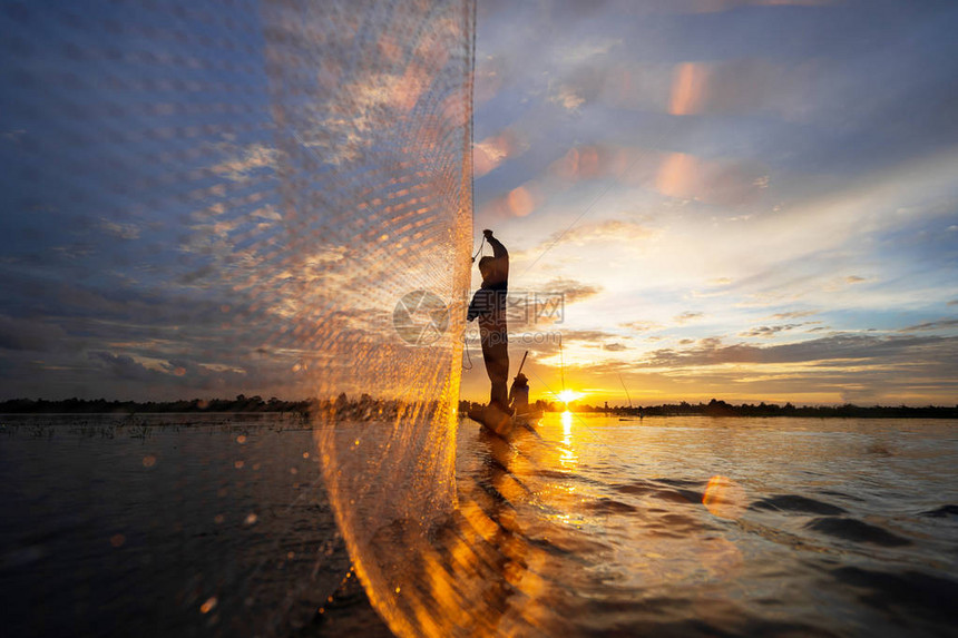泰国日落时在湖上挂网的渔船上的渔图片