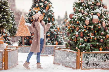 Beautidul女人在圣诞市场户外雪地里的枞树附近蓬松的雪正在飘落一背景图片