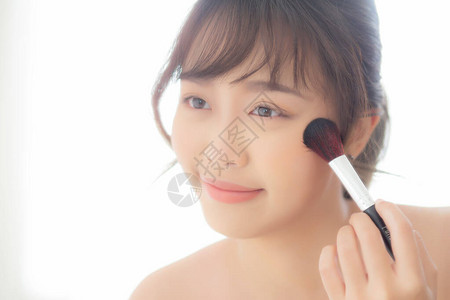 美容肖像年轻亚洲女微笑着面对在卧室里用刷子脸颊化妆图片