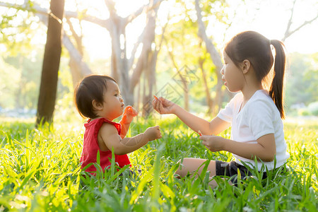 美丽的亚洲小孩子在夏天坐在公园里玩耍图片