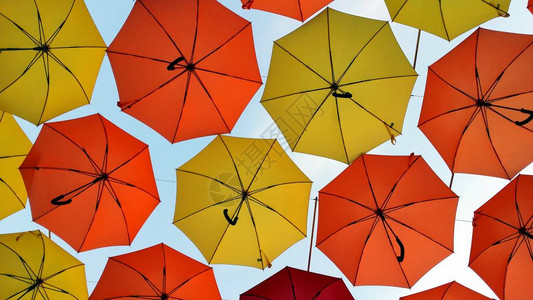 在城市街道上散步时打着五颜六色的雨伞图片