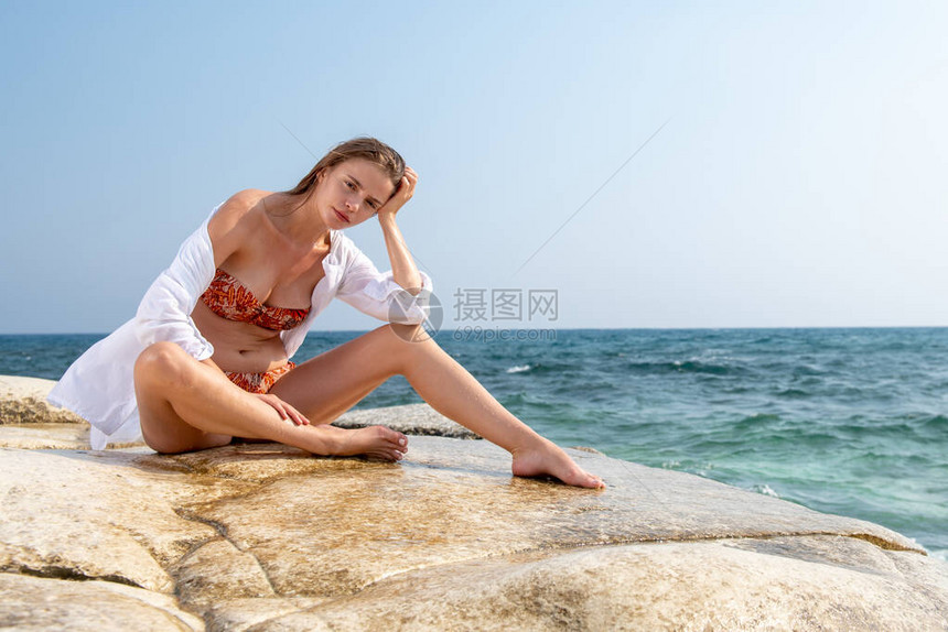 穿泳衣坐在沙滩上的白石上穿着泳衣的图片