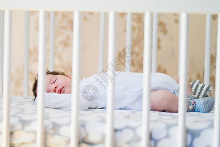 一个迷人的婴儿睡在婴儿床上图片