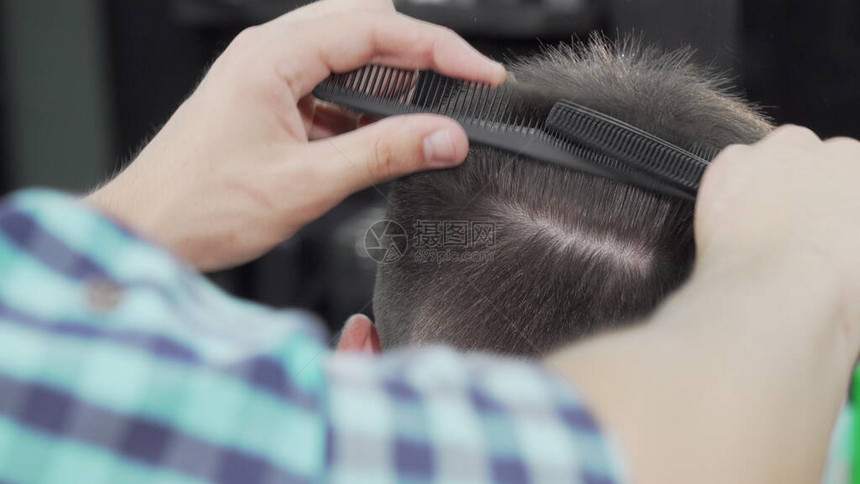一个专业理发师剪头发的短片在当地理发店接受新发型的面目全非的男顾客使用剪刀的发型师工图片