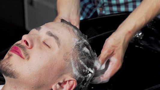 男人让专业发型师洗头发一位男顾客在理发店准备新发型的短片理发师洗一图片