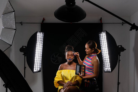 专业化妆师在摄影棚与非洲时装模特合作图片