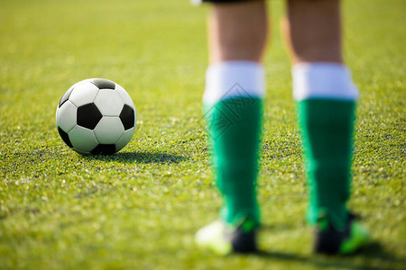 站在球旁边准备踢的一名足球运动员初级足球运动员的腿图片