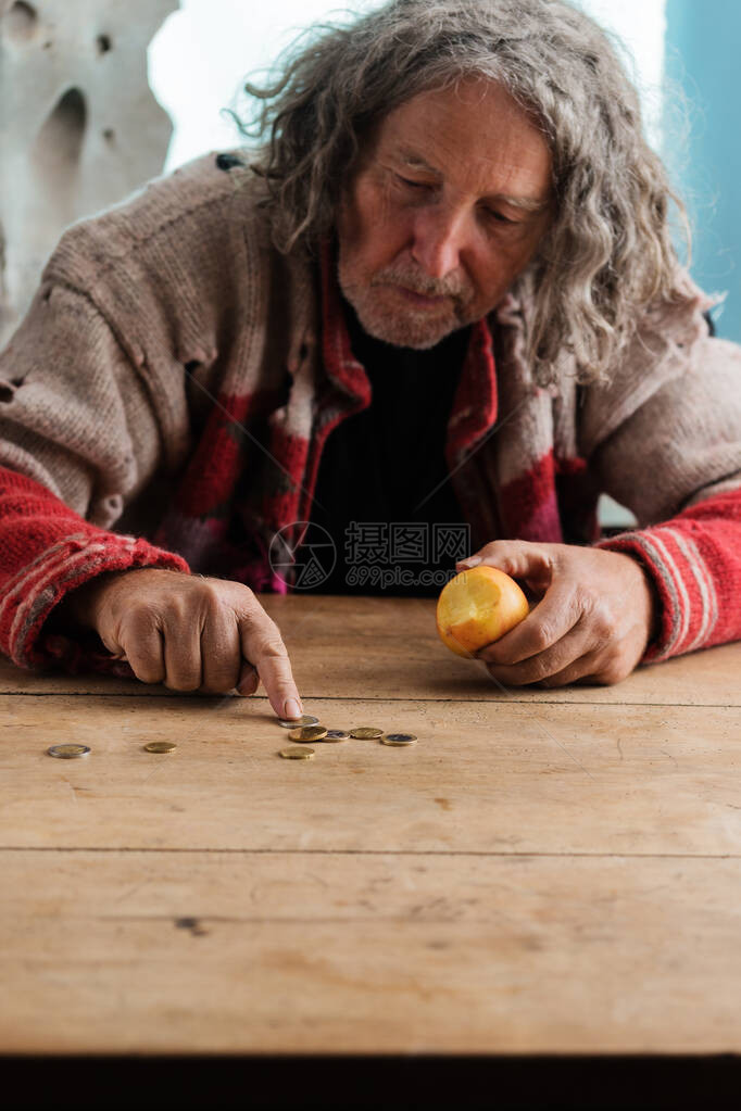 穿着撕破毛衣的老人在桌子上吃图片