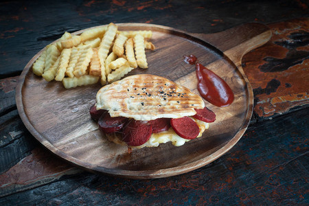 土耳其烤香肠和芝士三明治配有新鲜薯条在生锈的木制厨图片