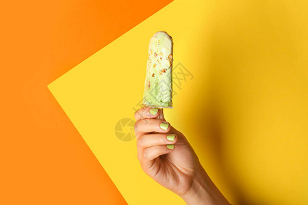 彩色背景上带美味开心果冰淇淋的女手图片