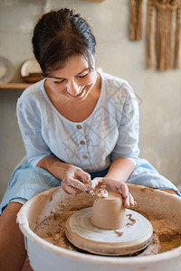 女陶工去除锅陶轮上的多余层塑造一个碗的妇女手工陶瓷艺图片