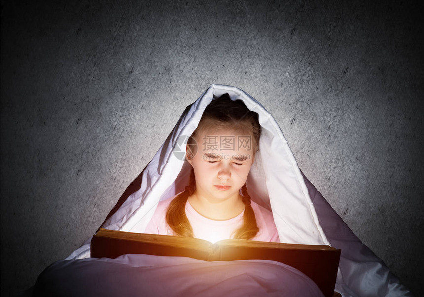 害怕的孩子带着打开的书和手电筒躲在毯子下害怕的女孩闭着眼睛躺在家里的床上孩子读童话穿着睡衣的女孩在墙壁图片