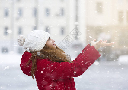 冬天来了年轻的红发女人玩雪花向上看城市背景图片