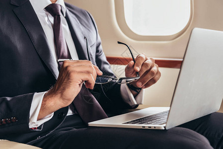 用手提电脑在私人飞机上佩戴眼镜的商图片