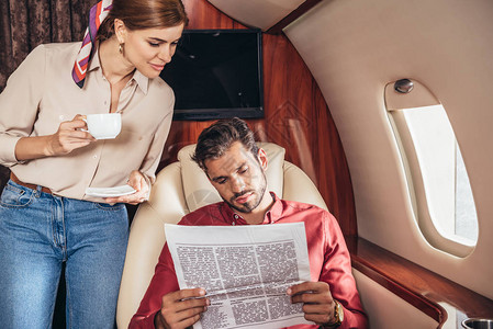 私人飞机上有杯子阅读报纸的男图片