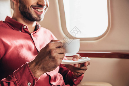 在私人飞机上拿着杯子的衬衫上微笑图片