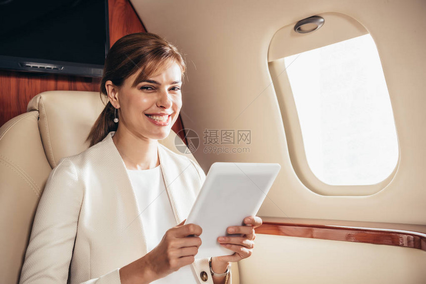 在私人飞机上使用数字平板电脑的身着西装图片