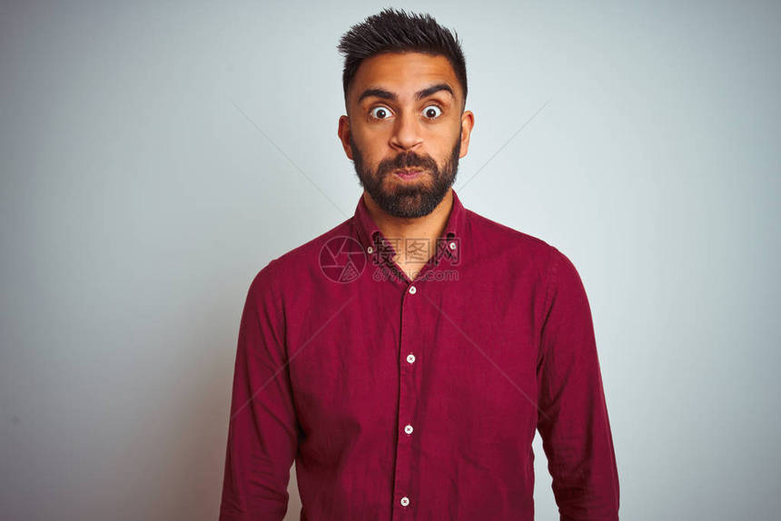 穿着红色优雅衬衣的印度年轻人站在孤立的灰色背景之上图片