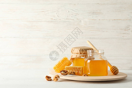 蜂窝胡桃花生配料和有木制背景蜂蜜的罐图片