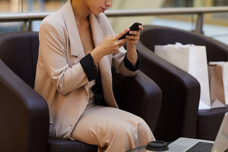 利用智能手机在购物中心复制空间放松时使用智能手机的优雅年轻女图片