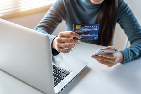 女使用信卡在手机和笔记本电脑上支付电子商务和在线购物概念图片