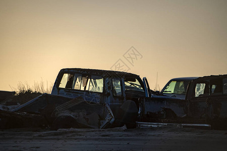 沙滩上日落时的废弃汽车剪影图片
