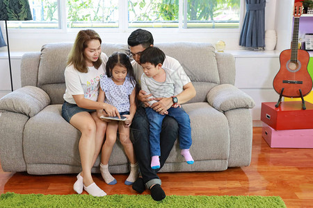 快乐的亚洲家庭教他们的孩子儿和女儿如何使用平板石图片