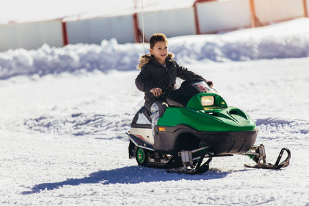 男孩在冬季风景中驾驶雪地摩托图片